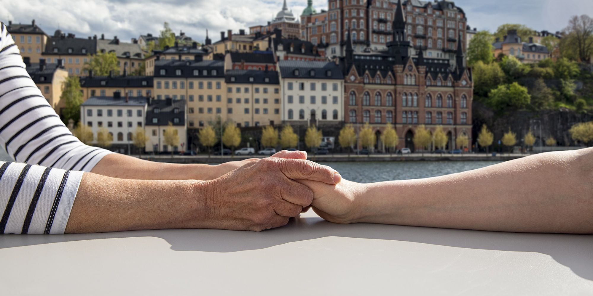 Par som håller hand med Södermalm i bakgrunden.