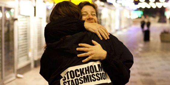En medarbetare från Stockholms Stadsmission kramar en människa på stan.