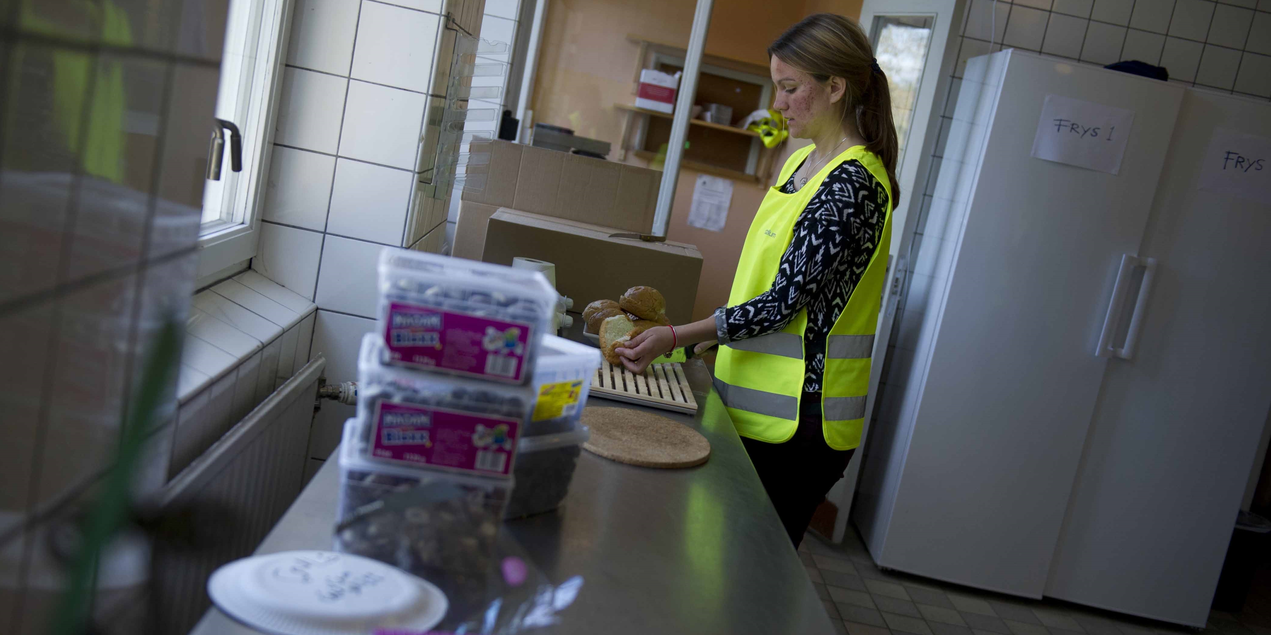 Volontären Johanna förbereder smörgåsar på Stockholms Stadsmissions familjeboende