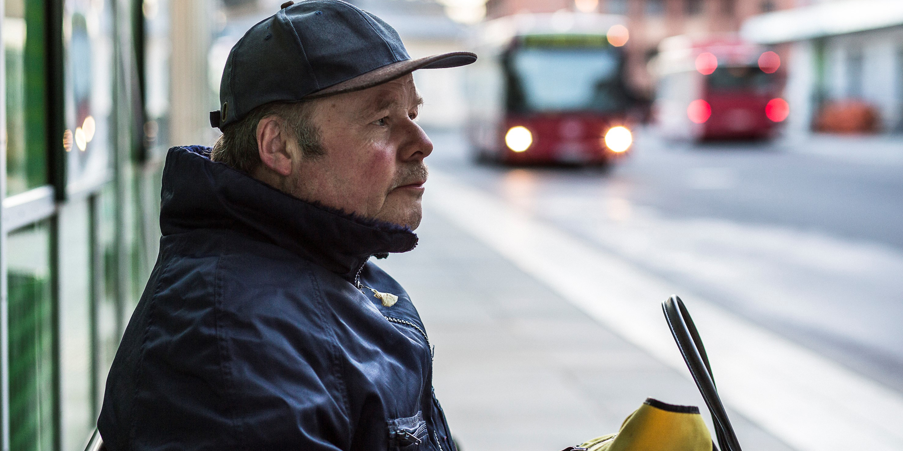 Man i keps som väntar på bussen
