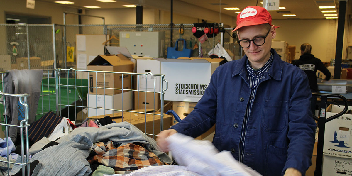 Arbetsträning på lager - en man sorterar textilier