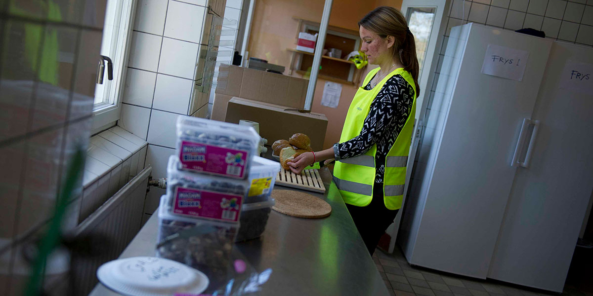 Volontären Johanna förbereder smörgåsar på Stockholms Stadsmissions familjeboende