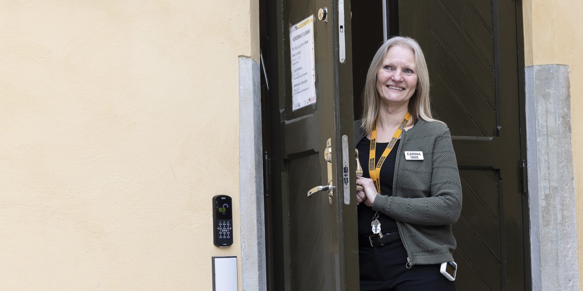 Mötesplatsvärden Carina står utanför dörren och tar emot besökare.