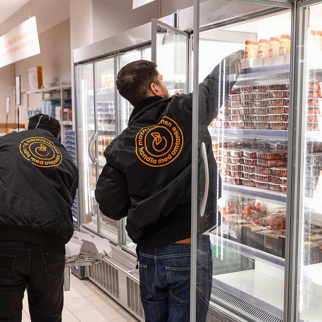 Bild på en medarbetare som sorterar in mat i en kyl i en Matmissionen-butik.