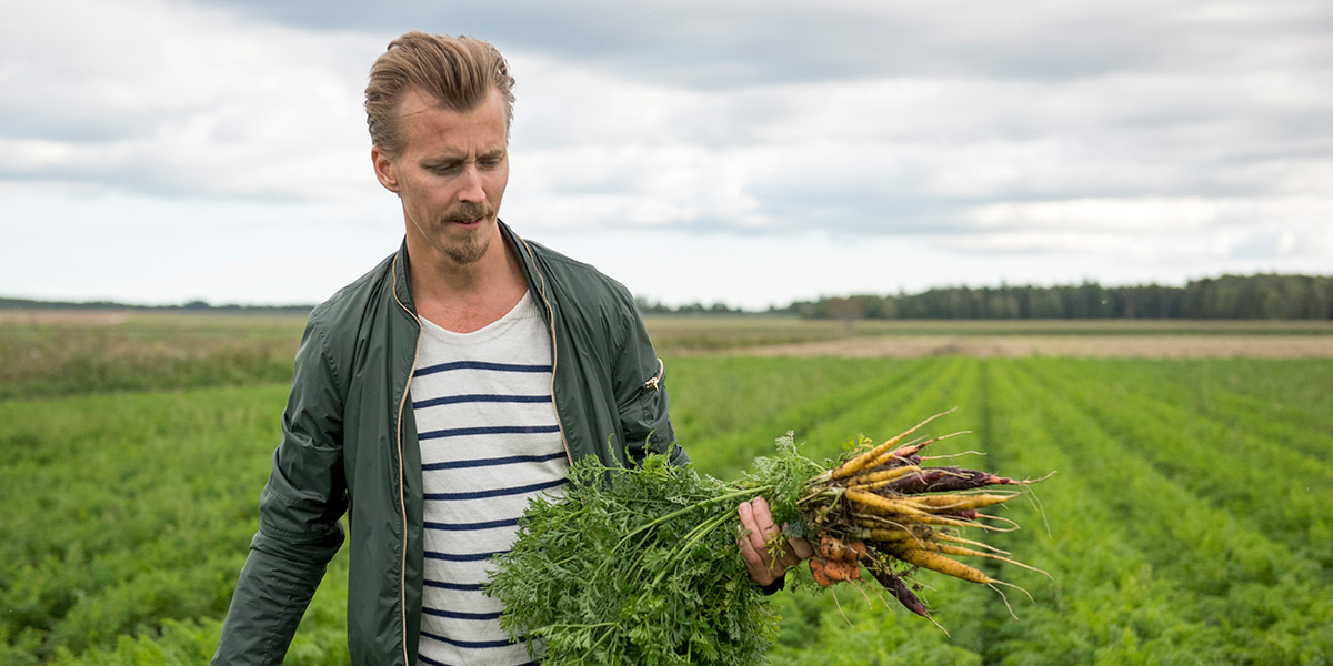 Paul Svensson står med morötter i handen.