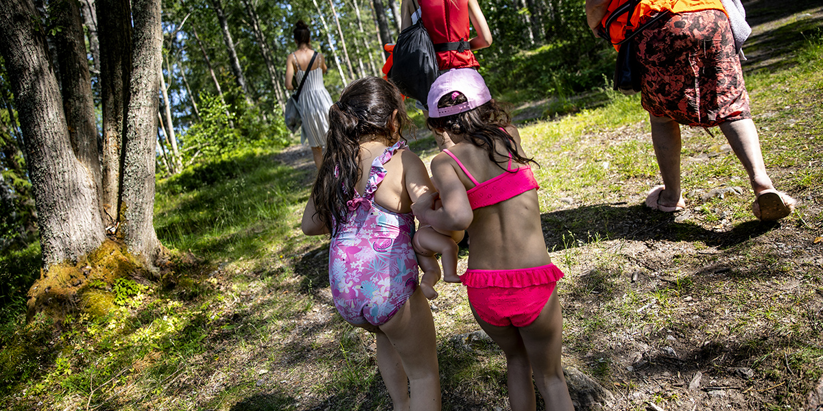 Barn som går tätt tillsammans genom skogen på väg tillbaka till sommarkollot.