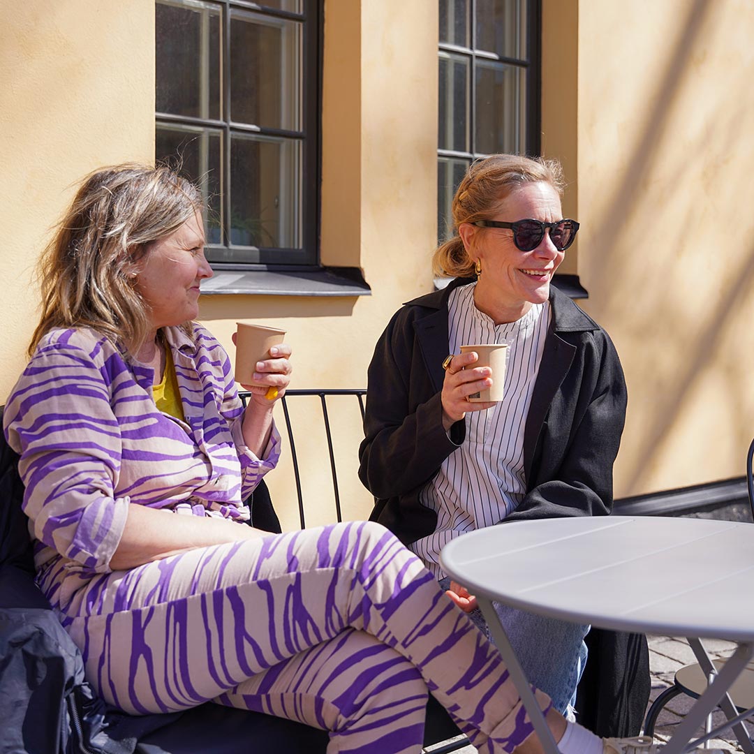 Två gäster dricker kaffe på uteserveringen på Stockholms Stadsmissions mötesplats vid Mariatorget.