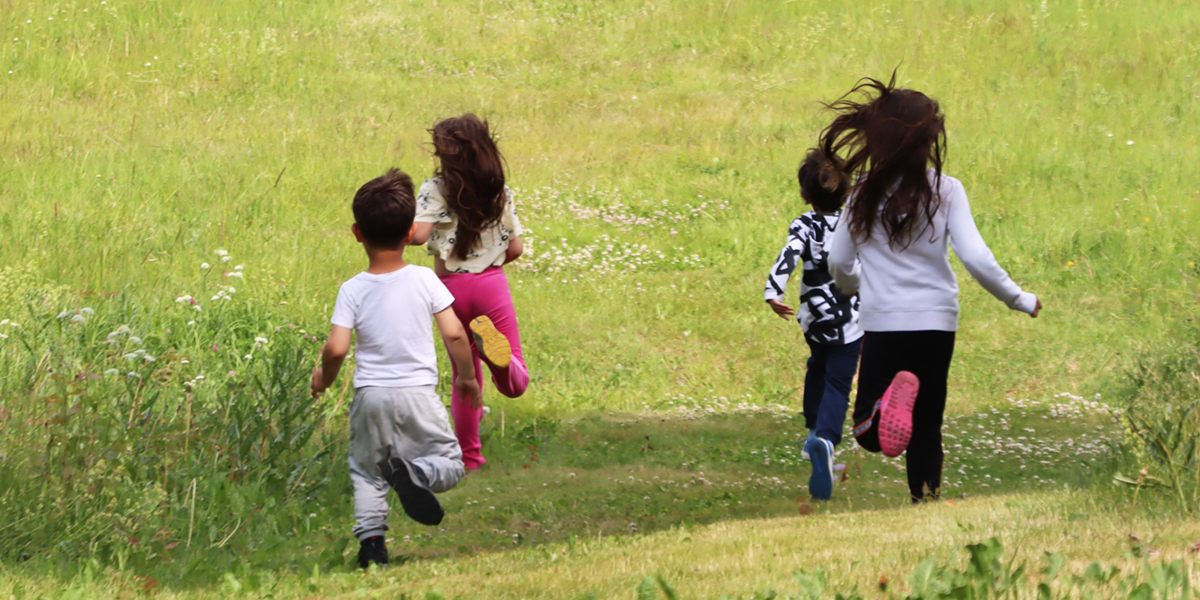 Barn springer på en sommaräng.
