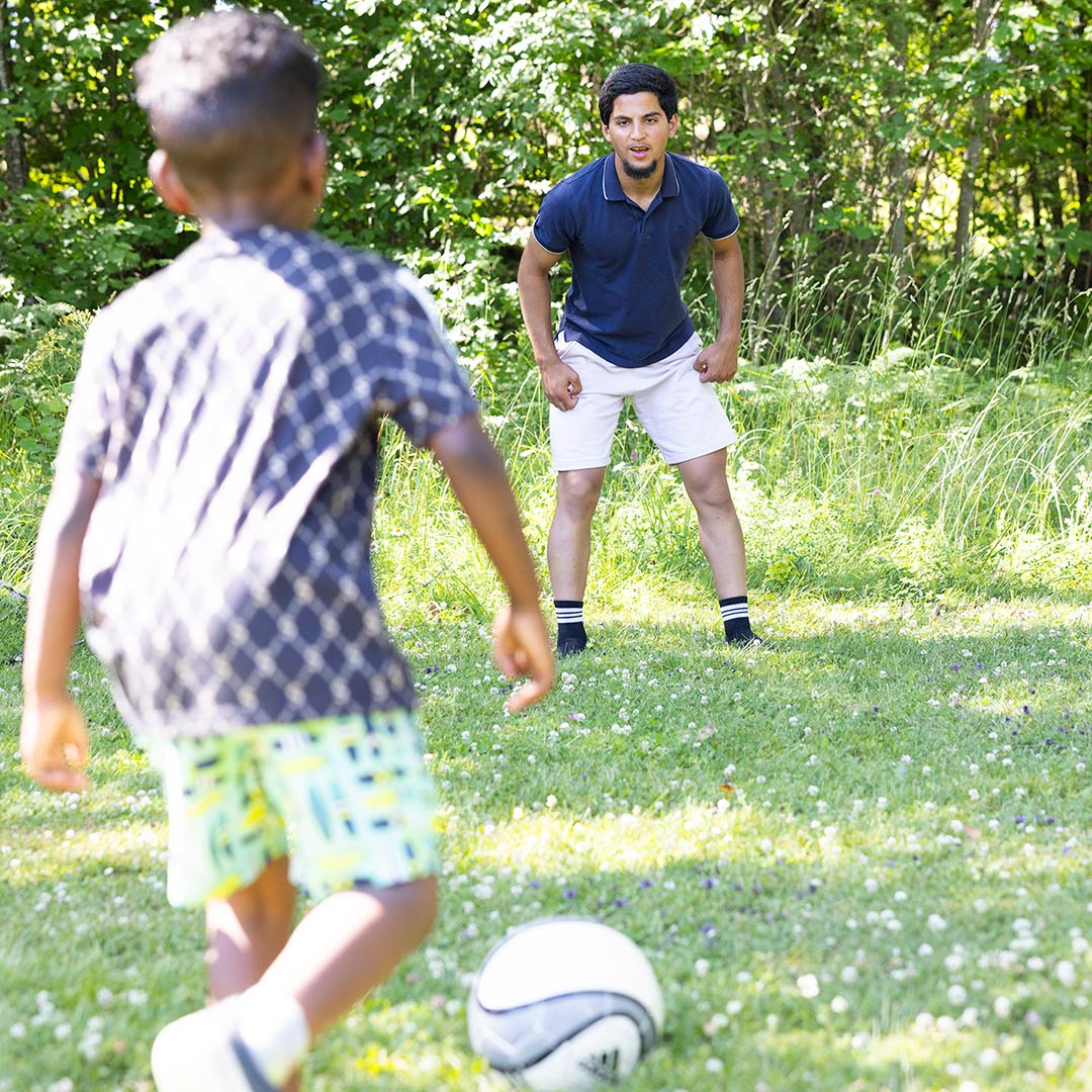 Kolloledare spelar fotboll med barn på Stockholms Stadsmissions sommarkollo.