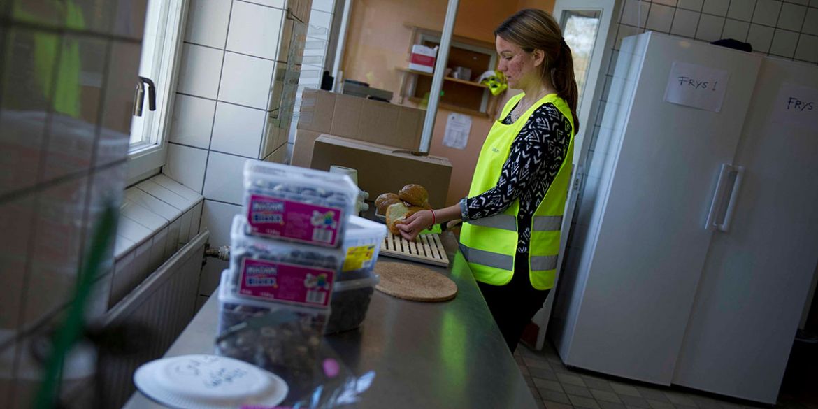 Volontären Johanna förbereder smörgåsar på Stockholms Stadsmissions familjeboende