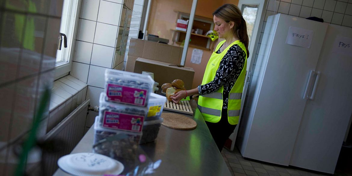 Volontären Johanna förbereder smörgåsar på Stockholms Stadsmissions familjeboende