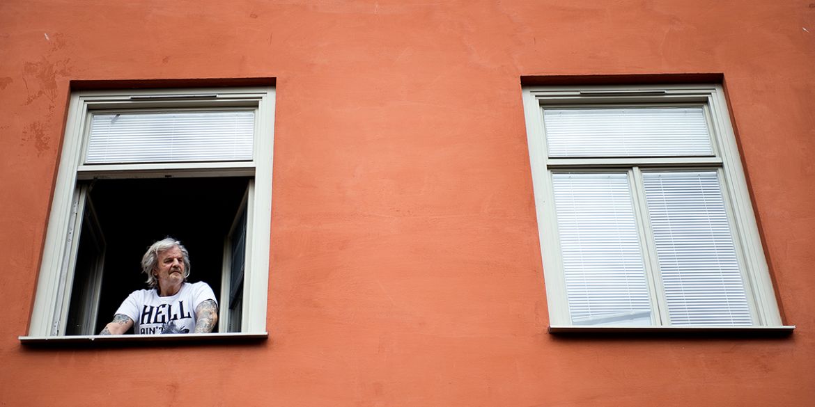 Person tittar ut från sitt fönster på Bostället