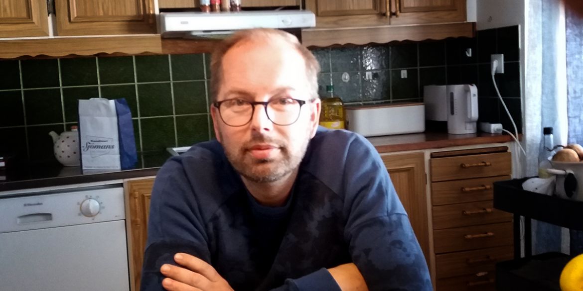Joachim sitter i sitt kök och ler in i kameran Joachim sitter i sitt kök och ler in i kameran