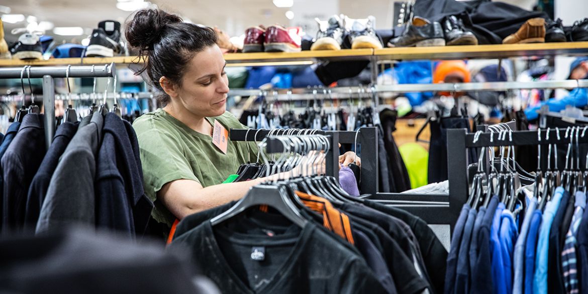 Arbetsträning i second hand-butik. Foto: Anna Z Ek Kvinna plockar med kläder i en butik.