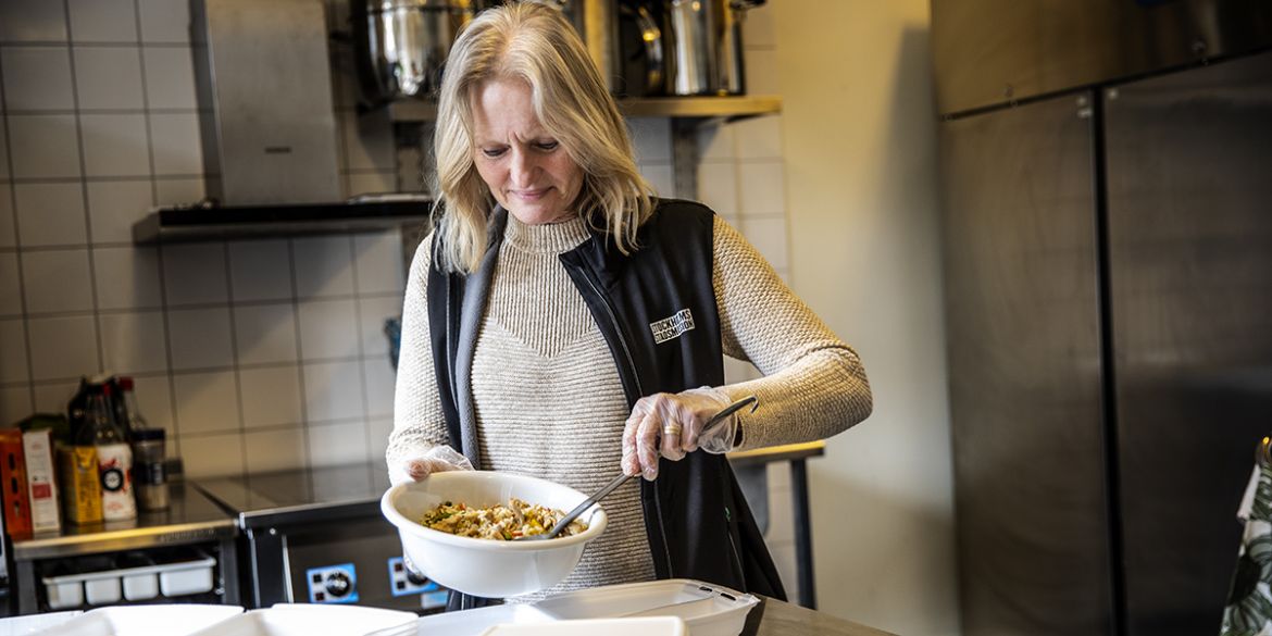 Matlådor levereras till äldre som isoleras på grund av covid-19. Kvinna gör iordning matlådor i St Paul.