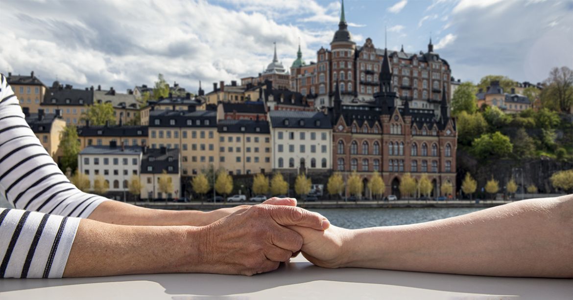 Par som håller hand med Södermalm i bakgrunden.