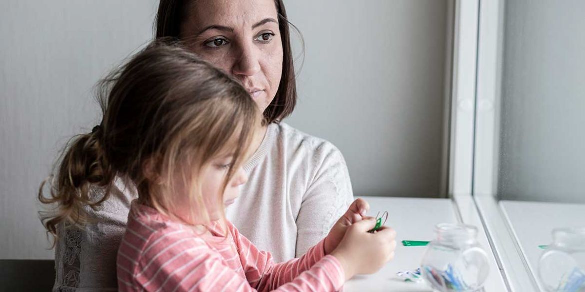 Mamma och flicka sitter vid ett fönster