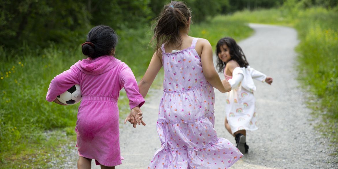 Barn springer hand i hand på en grusväg. Barnen är med i Stockholms Stadsmissions sommarkollo.