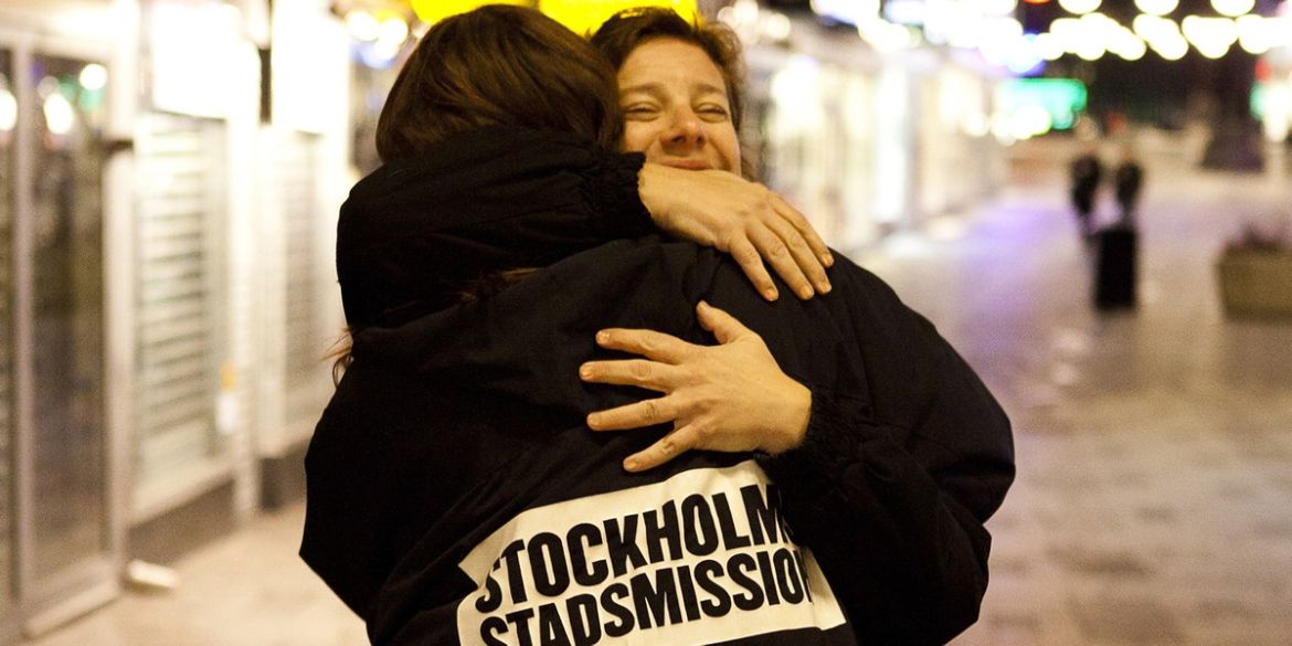 Medarbetare från Stockholms Stadsmission kramar en människa på stan..