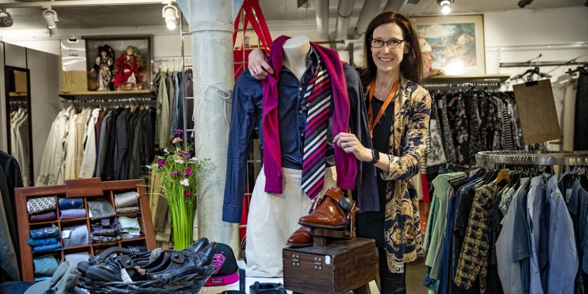 Monica, handledare på Stockholms Stadsmission, rättar till kläder på en skyltdocka.