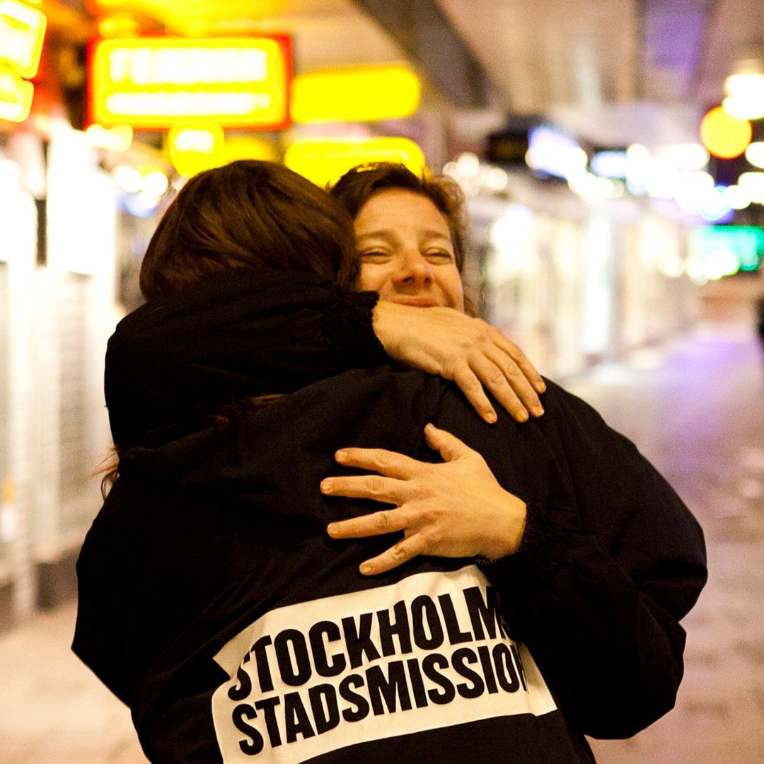 En medarbetare från Stockholms Stadsmissionen kramar om en människa på stan.