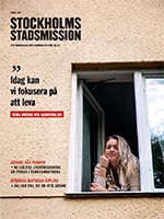 Framsidan på Stockholms Stadsmissions tidning. En kvinna tittar ut genom ett fönster på ett flerfamiljshus.