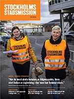 Framsidan på Stockholms Stadsmissions tidning. Två kvinnor i varselvästar går på en trottoar.