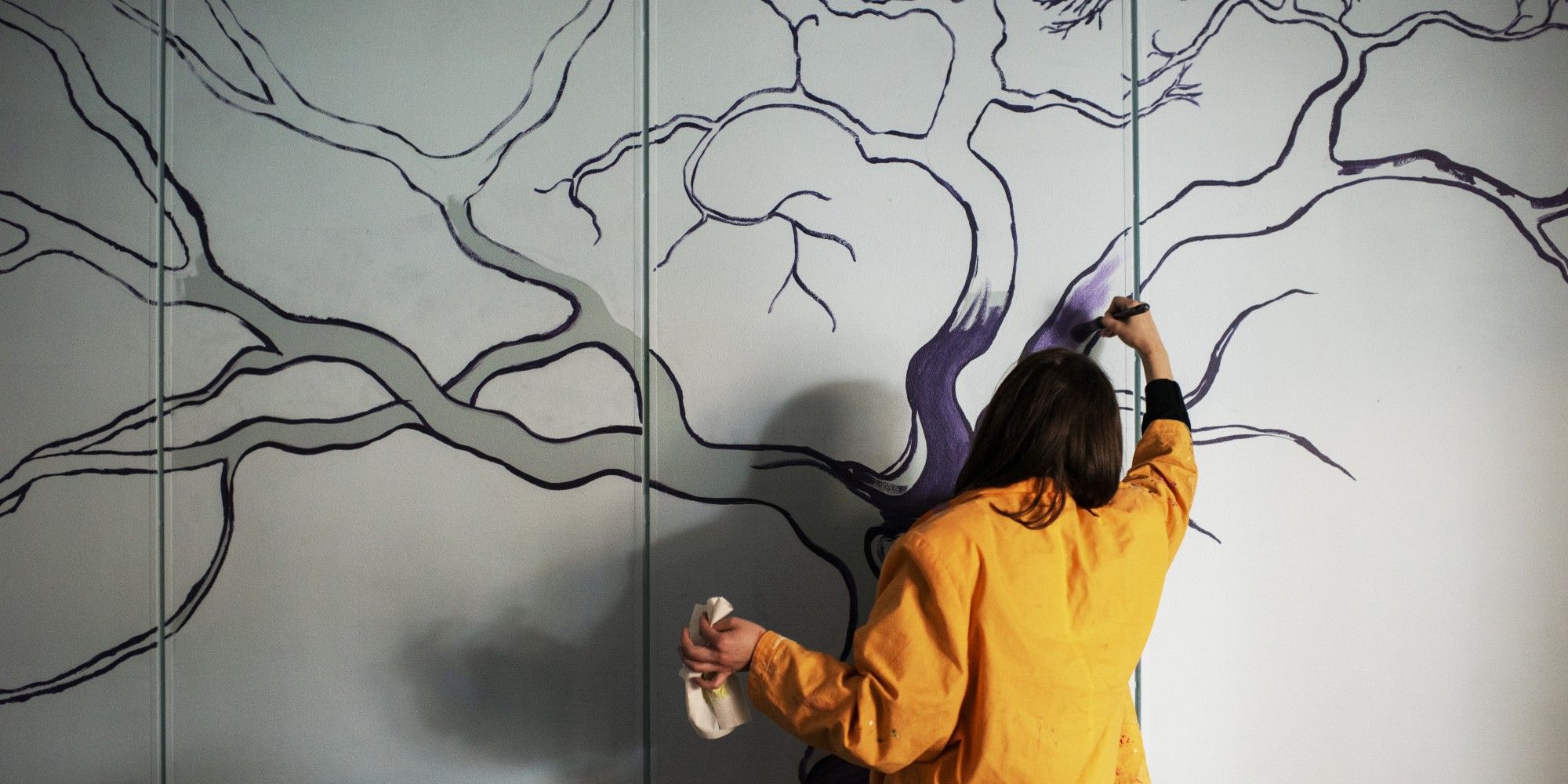 En deltagare på Stadsmissionens Folkhögskola målar på väggen.