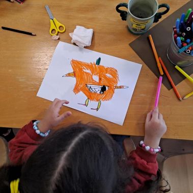 Ett barn på Stockholms Stadsmissions höstlovskollo ritar en pumpa.