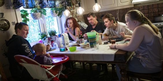 Familj sitter runt ett bord och äter