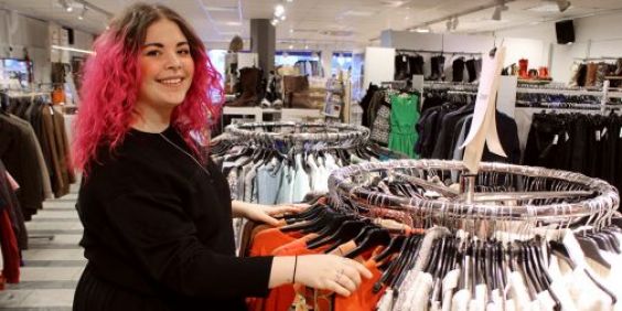 Glad tjej står i klädbutik