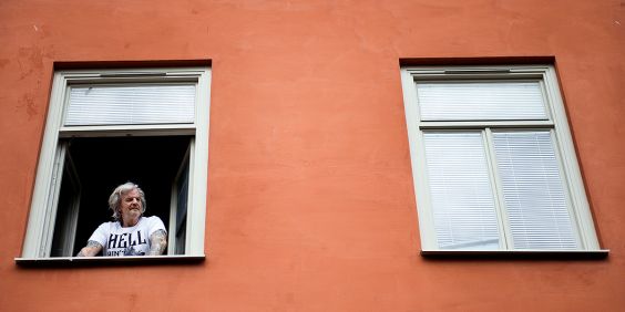 Man tittar ut genom ett fönster på ett bostadshus.