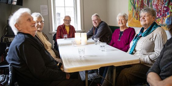 Årsrika personer sitter runt ett bord och samtalar.