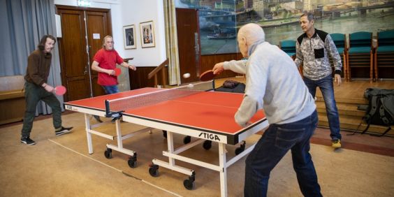 Tre män spelar bordtennis.