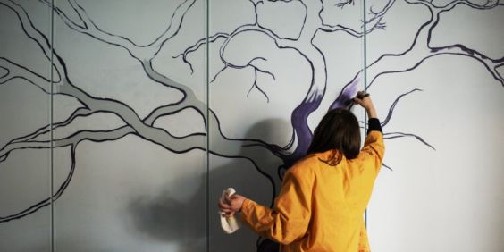 En elev på Stadsmissionens Folkhögskola målar på väggen.