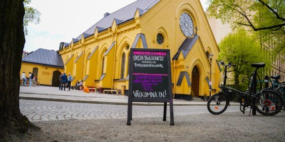 En gatupratare framför Stockholms Stadsmissions Mötesplats Mariatorget tipsar om dagens lunch.