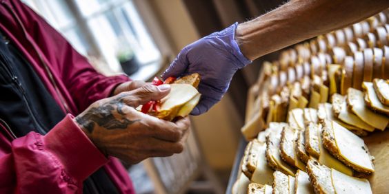 Stadsmissionen mobiliserar för att ha öppet trots coronaviruset. Man får smörgås i St Paul.