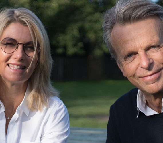 Kvinna och man tittar in i kameran och ler.