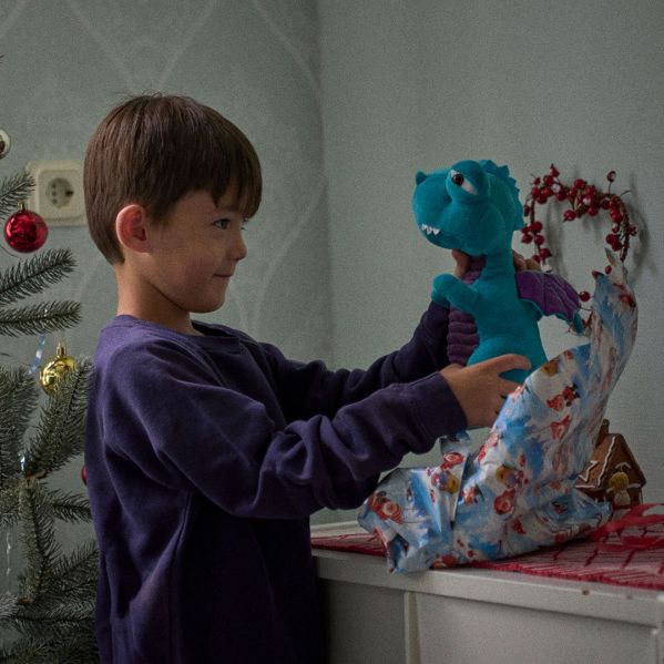 En pojke öppnar en julklapp. 