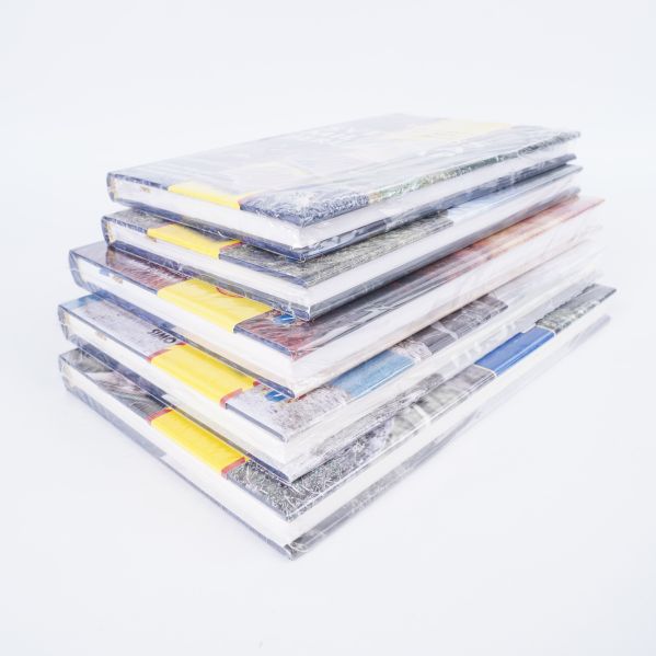 Hög med fem hårdpärmsböcker i plastförpackning, staplade snett