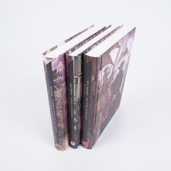 Tre böcker stående snett från ovan med synliga ryggar och omslag