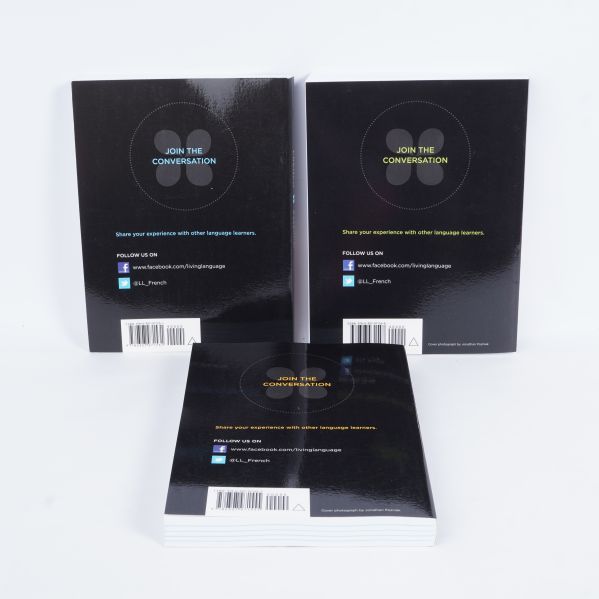 Baksidor på tre språkböcker med text och streckkoder