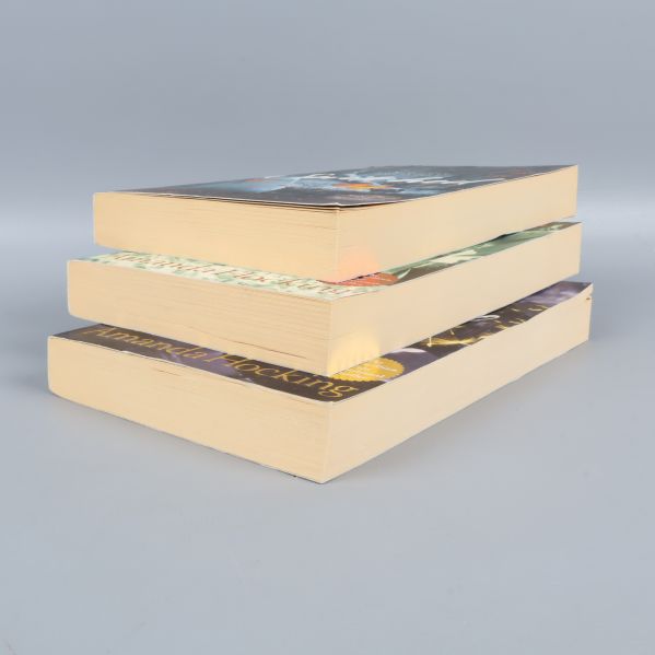 Tre pocketböcker lagda på hög, visar tjocklek och bladsidor