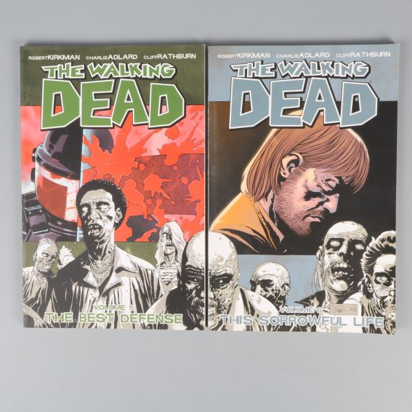 Två grafiska romaner från The Walking Dead staplade på grå bakgrund