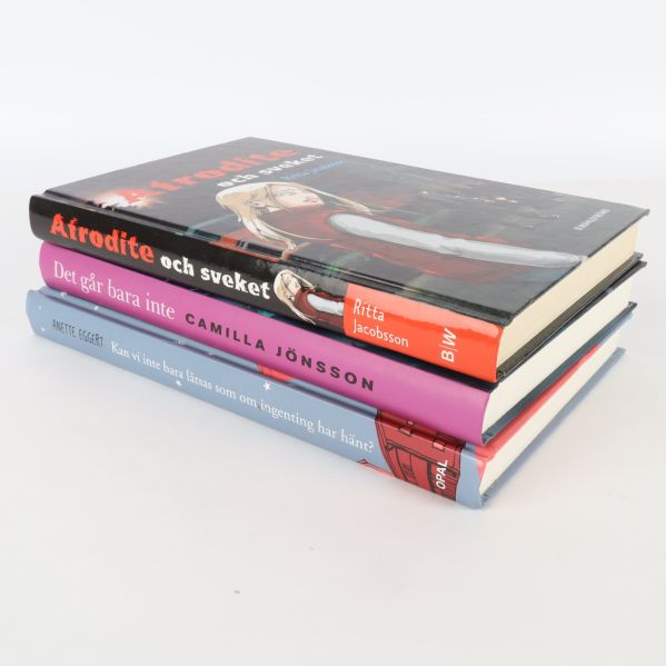 Tre böcker staplade, synliga ryggar och omslag