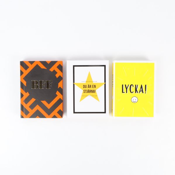 Tre böcker med glada omslag i orange, vitt och gult, titlar synliga