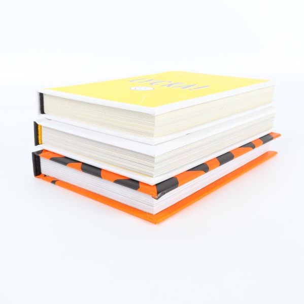 Tre böcker staplade på varandra, färgglada omslag syns