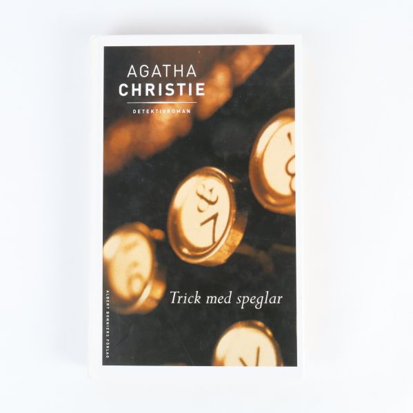 Framsidan av boken Trick med speglar av Agatha Christie med guldfärgade skrivmaskinstangenter