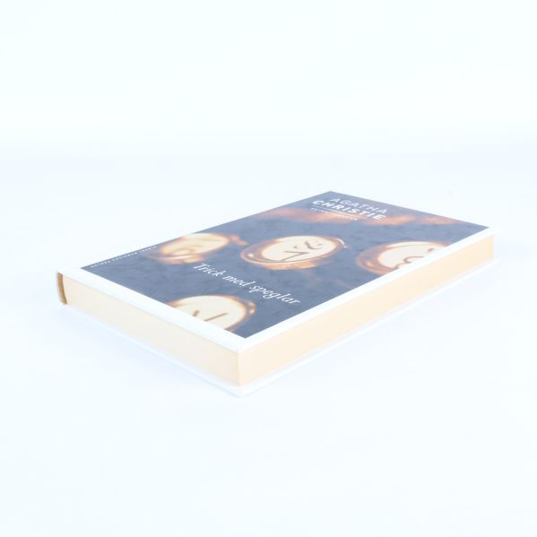 Boken Trick med speglar av Agatha Christie sedd från sidan, liggande på ett vitt underlag