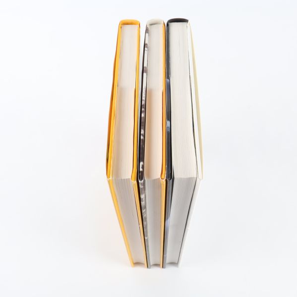 Överblick av tre böcker stående, med olika tjocklek och färg